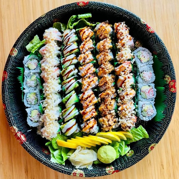A large platter of Awi Sushi rolls, including California, avocado, and spicy tuna, with ginger and wasabi.