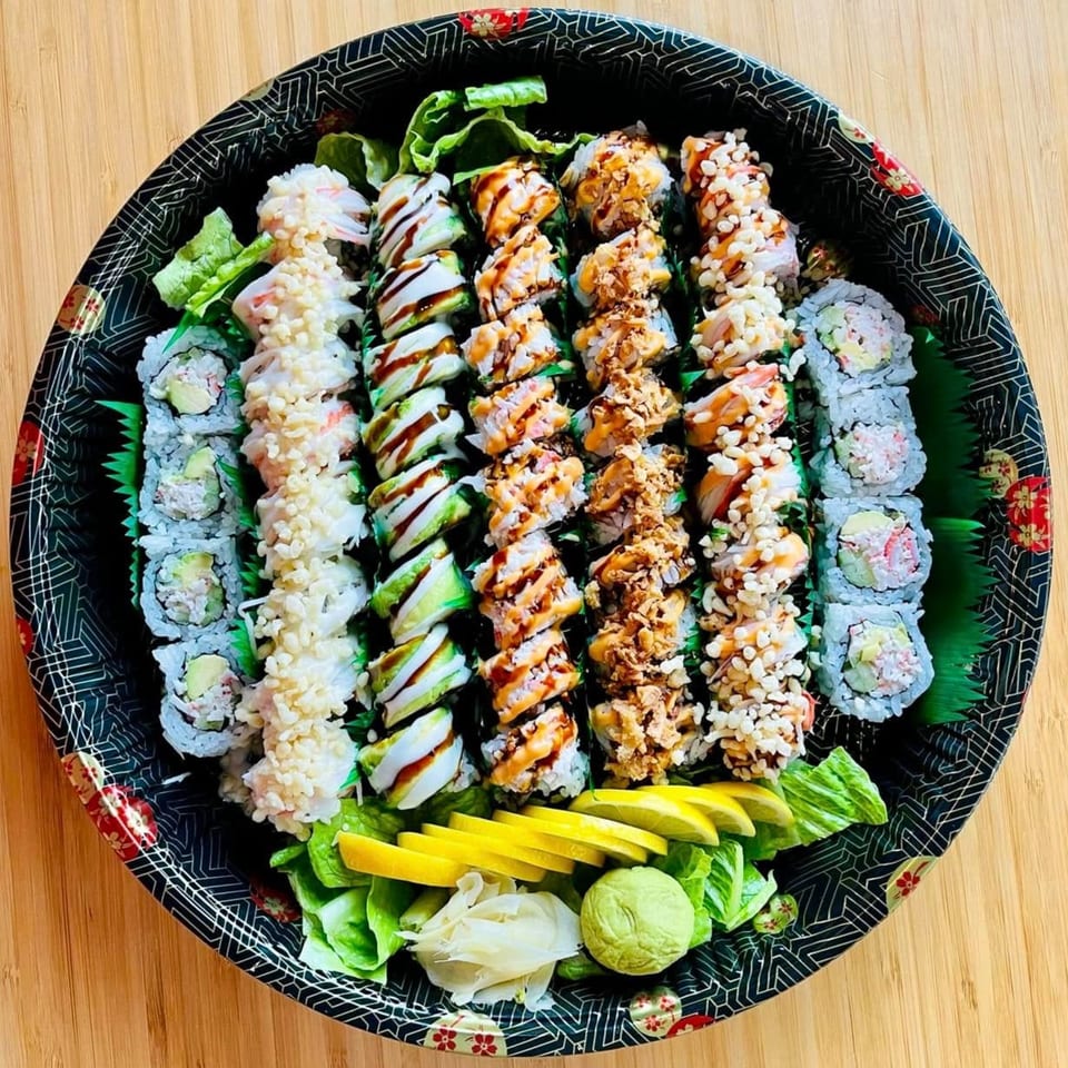 A large platter of Awi Sushi rolls, including California, avocado, and spicy tuna, with ginger and wasabi.