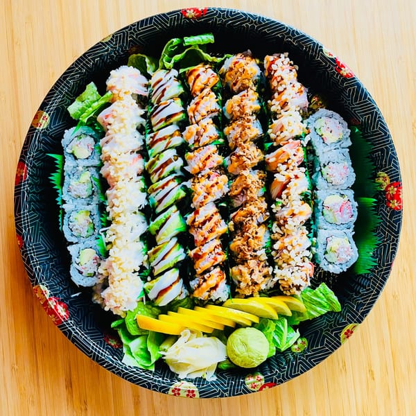 A large platter of assorted Awi Sushi rolls, including California, avocado, and crunchy rolls.