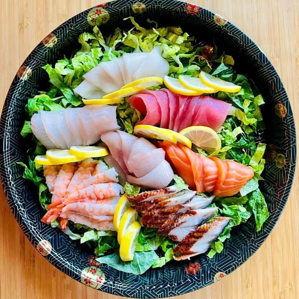 Awi Sushi's sashimi salad with various fish, shrimp, and lemon slices on a bed of lettuce.